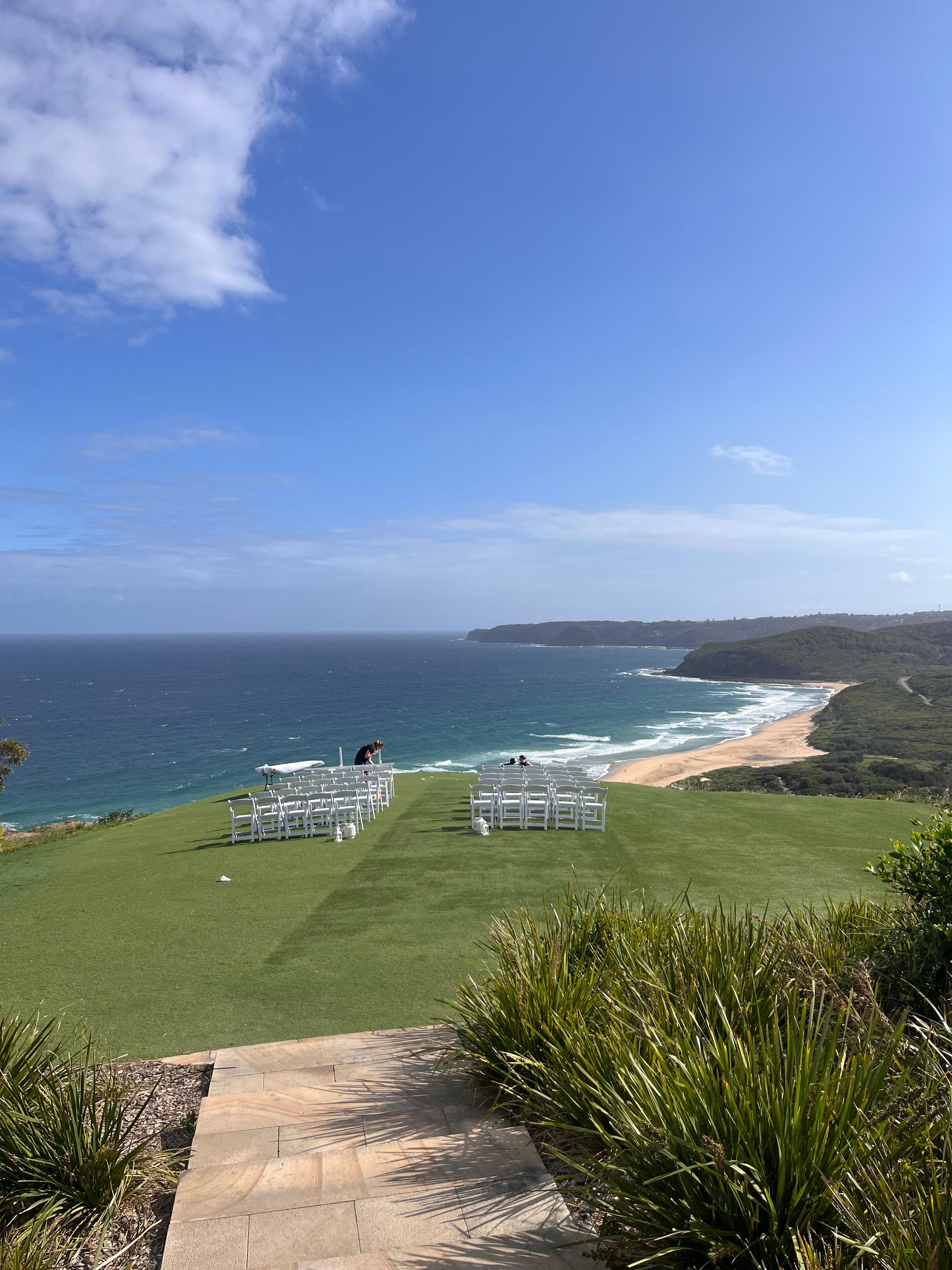 A grassy clifftop above the ocean and a long beach